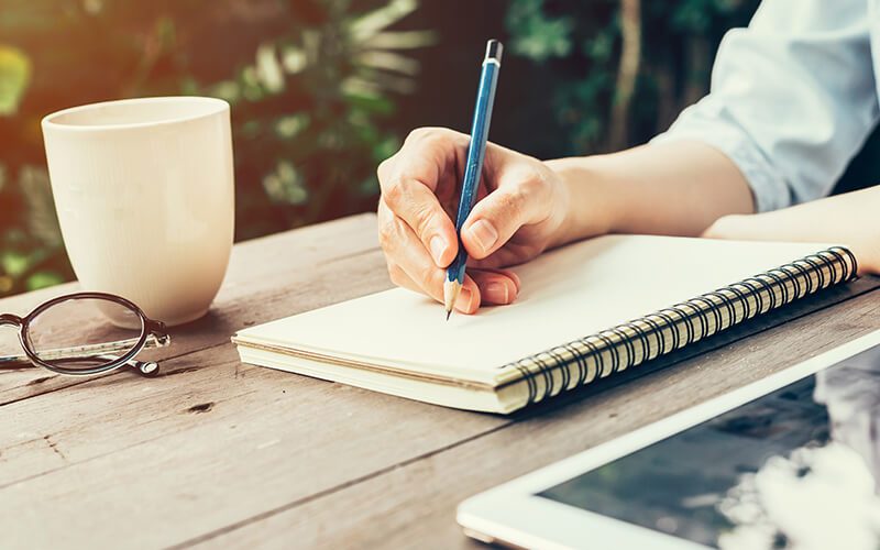 Student writing a strong thesis statement in notebook